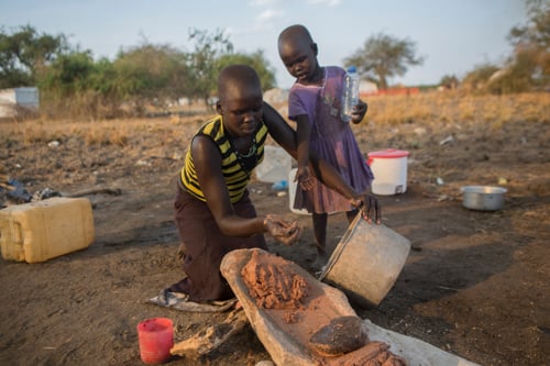 Leann Chol, 15, shares food with a young friend while preparing a simple meal for her family.