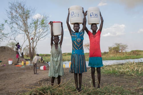 From left: Wara Nyuku, Ayol Awuat and Atieng Aluong carry water from the Nile in containers from CRS. Before receiving containers, they made up to 10 trips a day to collect water.