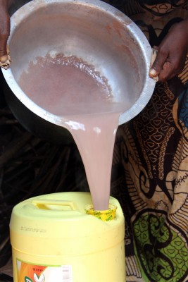 Lucy pours the fresh porridge into a container she can carry while selling it. Photo copyright 2015 Unbound. All rights reserved.