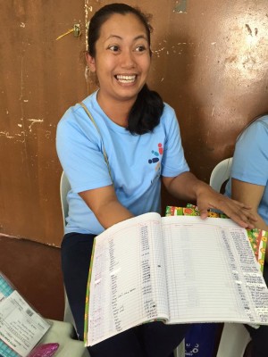 A volunteer bookkeeper from Unbound's Family Savings Program opens her accounts for us. She's received leadership and financial training to hold this important role in her small community's savings and lending program.