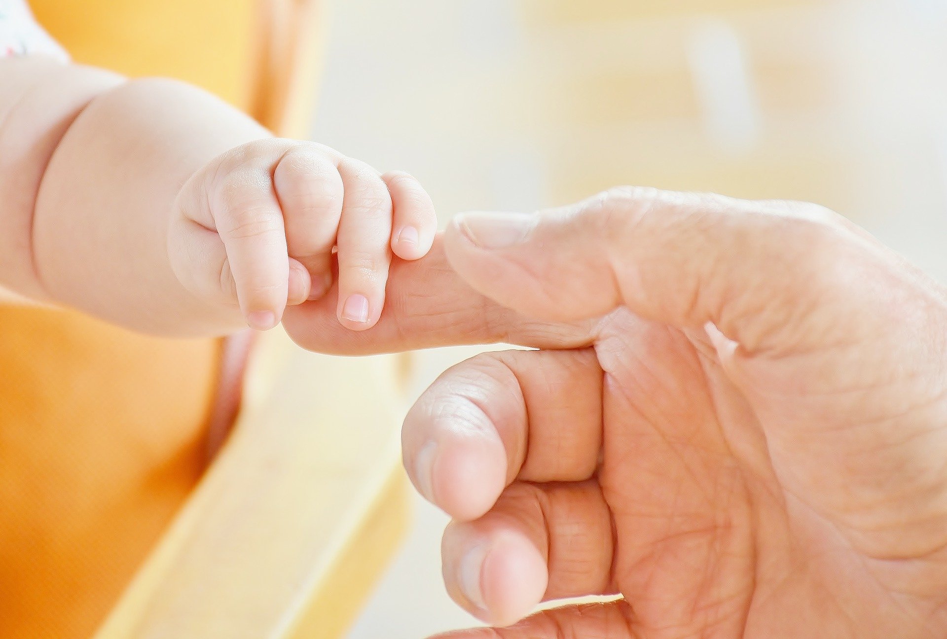 baby hand holding adult's finger