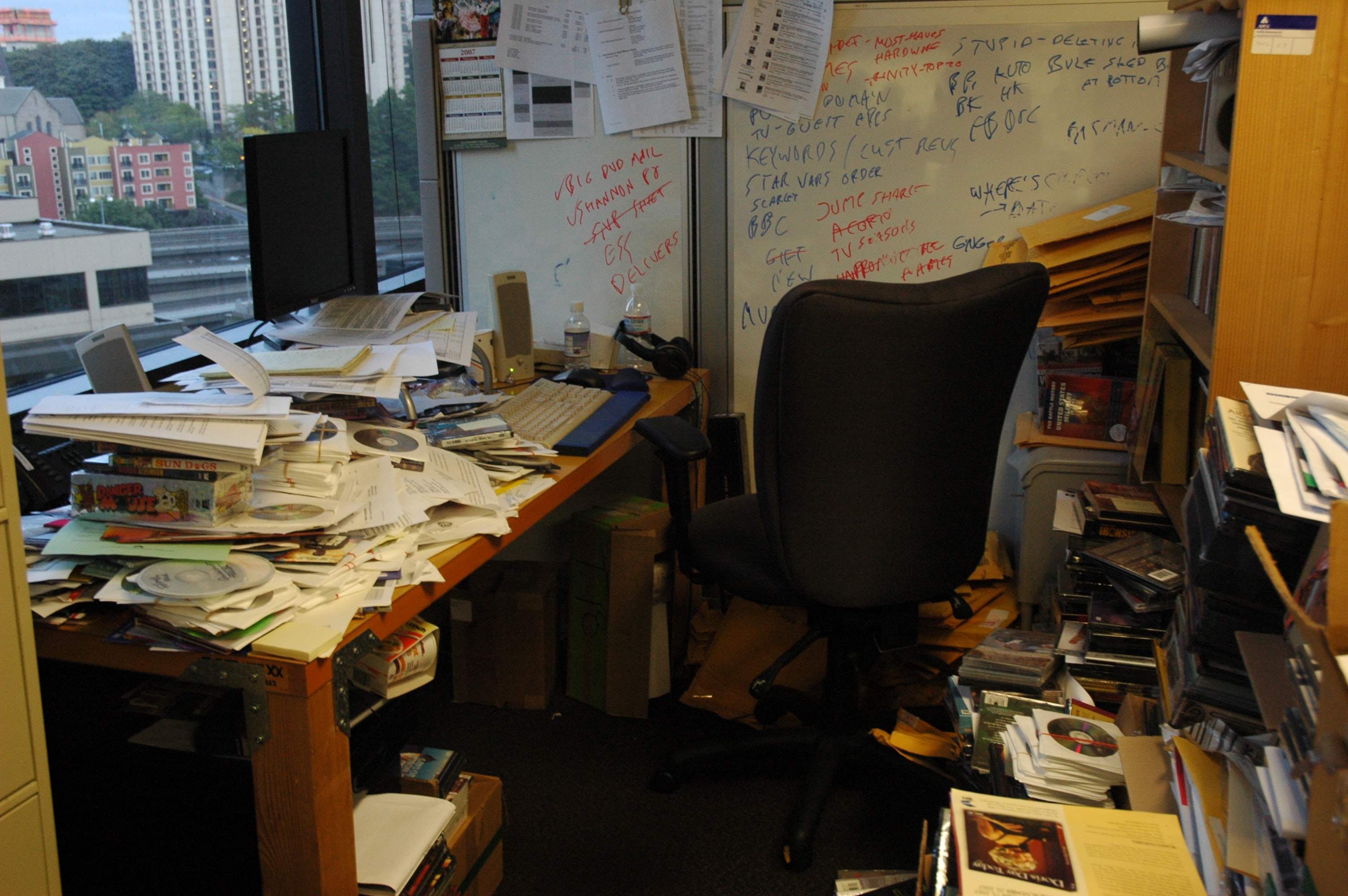 cluttered office with piles on desk and floor